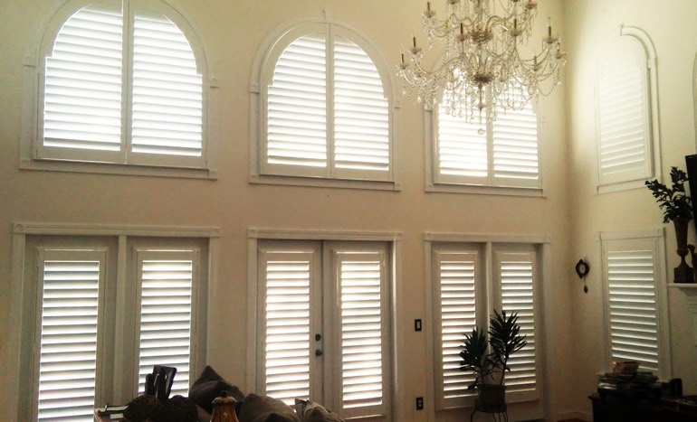 TV room in open concept Phoenix house with plantation shutters on high ceiling windows.