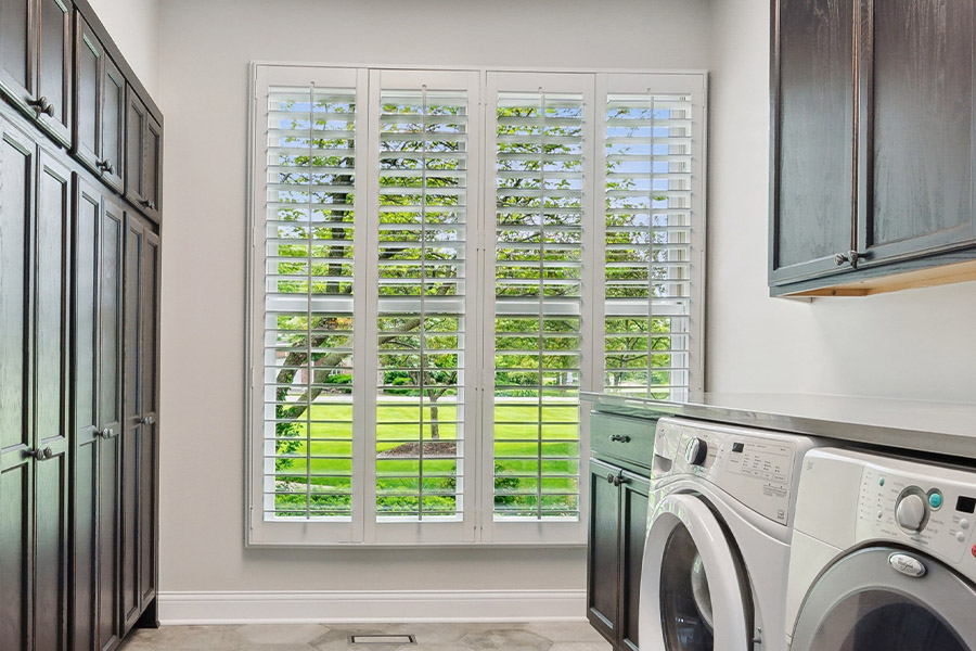Find the perfect level of natural light for your Phoenix laundry room with interior shutters. White Polywood shutters letting light through a laundry room window