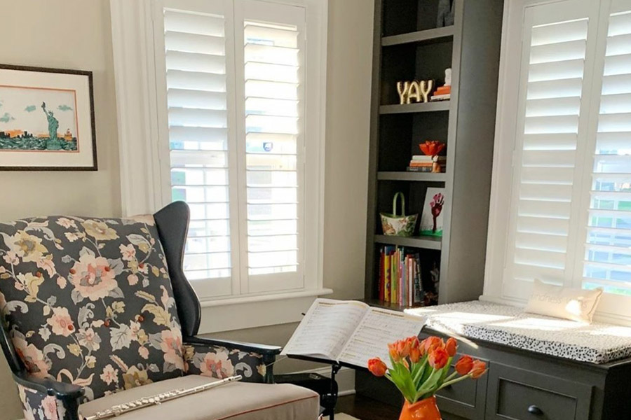 White Polywood shutters in a cozy and small living room with a bookshelf in the corner.