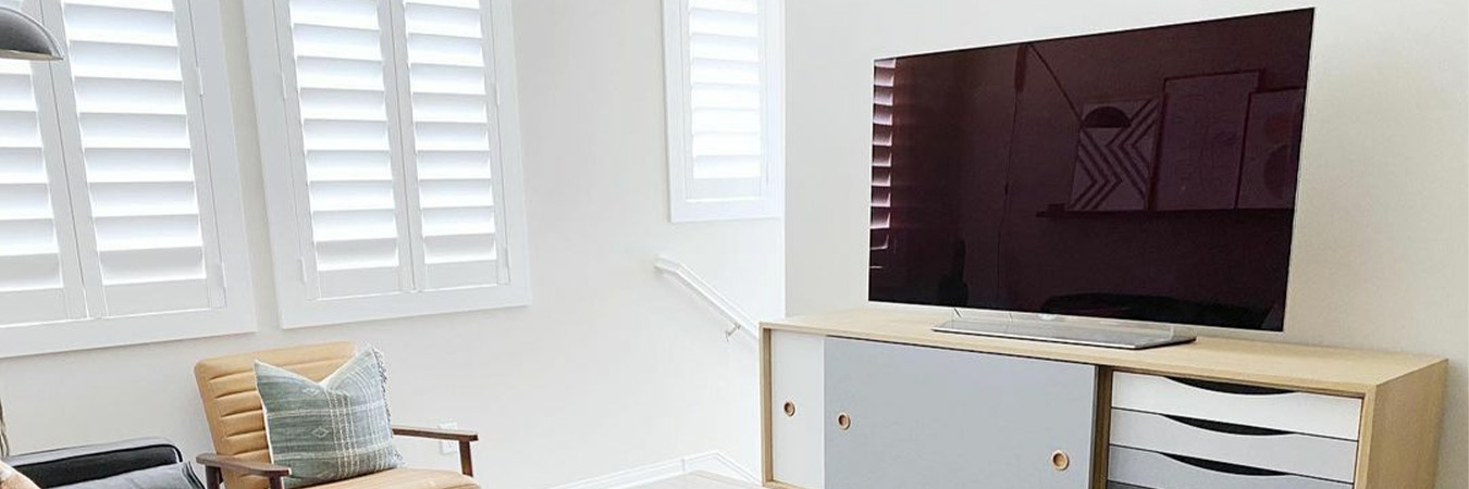 Photo Credit: Audrey Crisp Modern living room with a large tv screen and white polywood shutters.