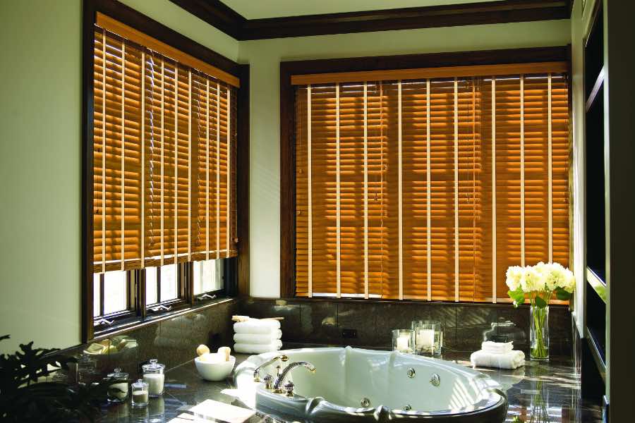 Premium quality blinds are always a stylish accent in your Phoenix home. Brown wood blinds on large windows in a green bathroom