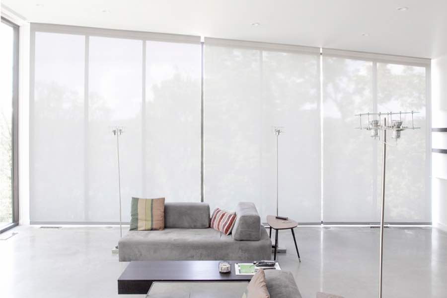 Motorized window shades make controlling natural light effortless in your Phoenix great room. White motorized shades on a wall of tall great room windows