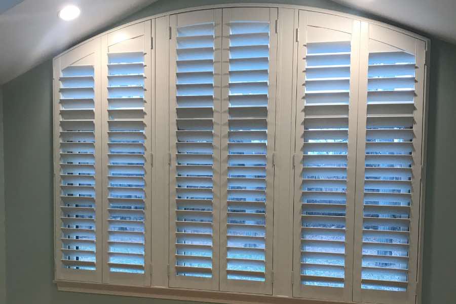 No window treatments are easier to clean on tall windows than interior shutters! White Polywood shutters on a large arched window