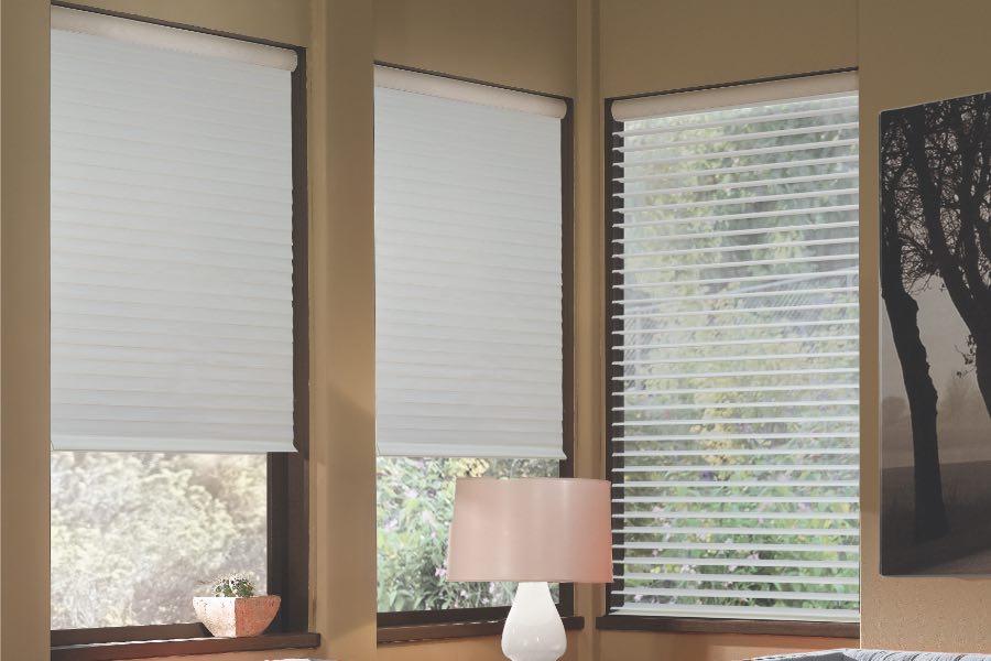 Opaque motorized window shades in Phoenix keep hot UV rays out of your home. Gray motorized sheer shades on corner windows next to gray furniture