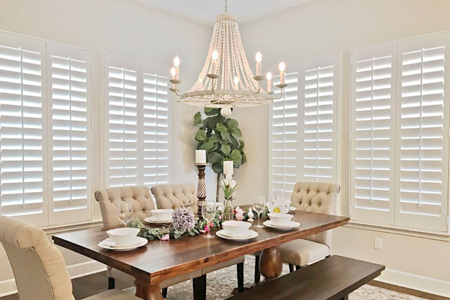 Polywood interior shutters offer style and durability. White Polywood shutters on large dining room windows.