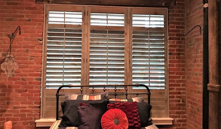 Reclaimed wood shutters add an organic touch to your minimalist spaces. Reclaimed wood shutters near a brick wall.
