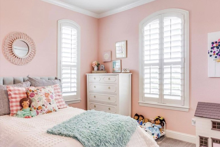 White Polywood shutters on arched windows in a pink child's bedroom. White Polywood shutters on arched windows in a pink child's bedroom.