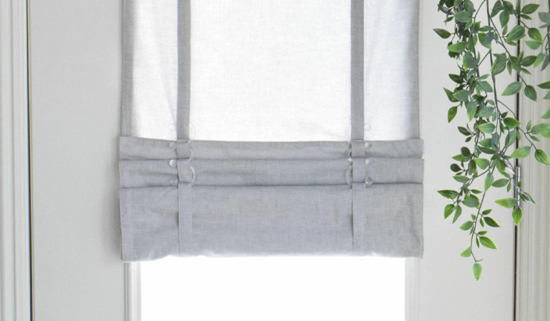 With a tiered tumble shade in Phoenix, you can block sun glare all year round. Gray rolled tumble shade on a glass door