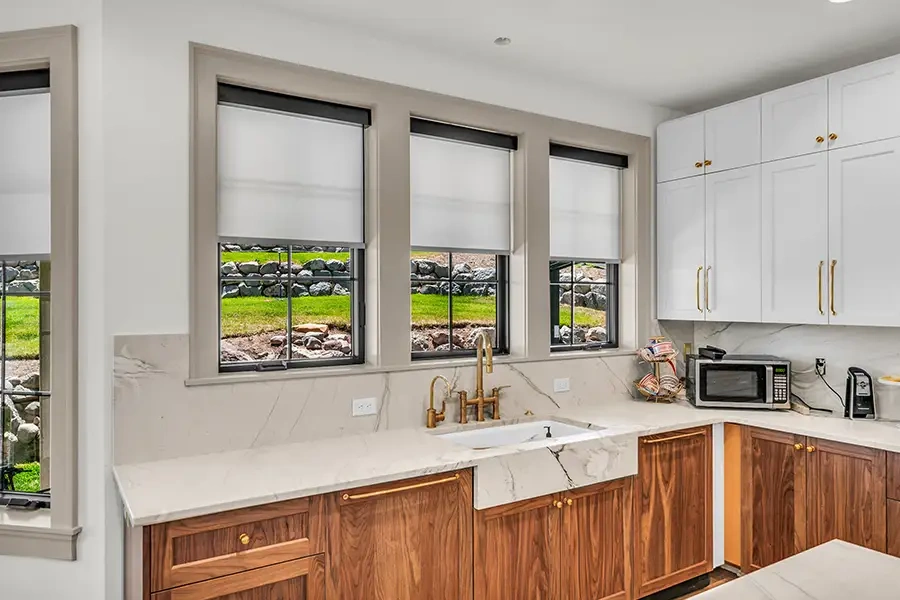 Slim white roller shades on three windows in a kitchen